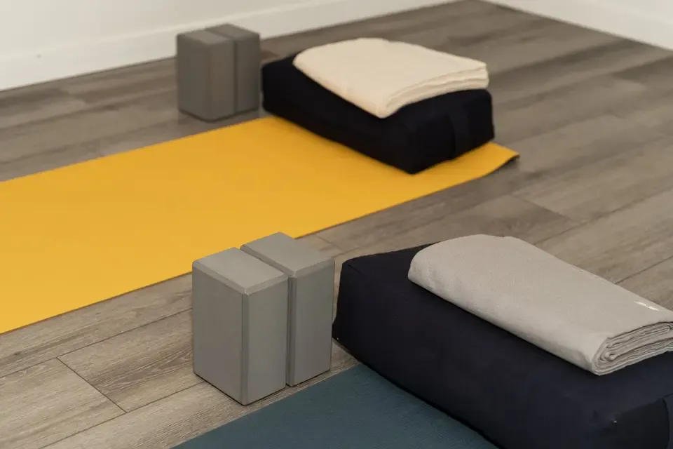Yoga mats and folded blankets on a wooden floor