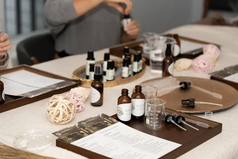 A table with aromatherapy oils, droppers, beakers, and informational flyers, suggesting a scent or wellness workshop setting.