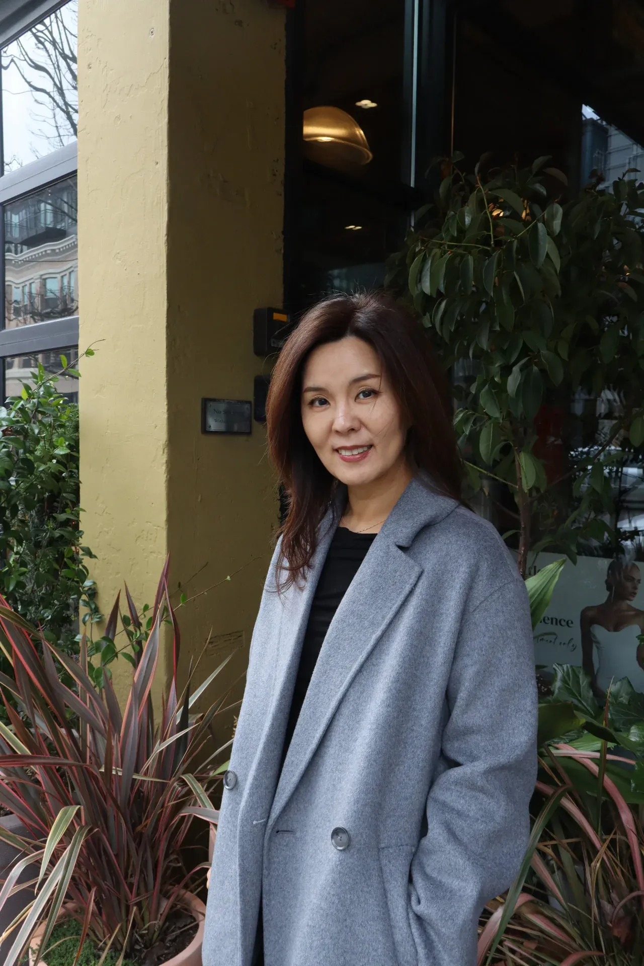 Portrait of Hye Young Kim standing outdoors in a grey coat
